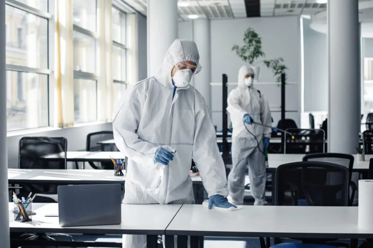 Desinfektion einer Arbeitsfläche mit Schutzausrüstung
